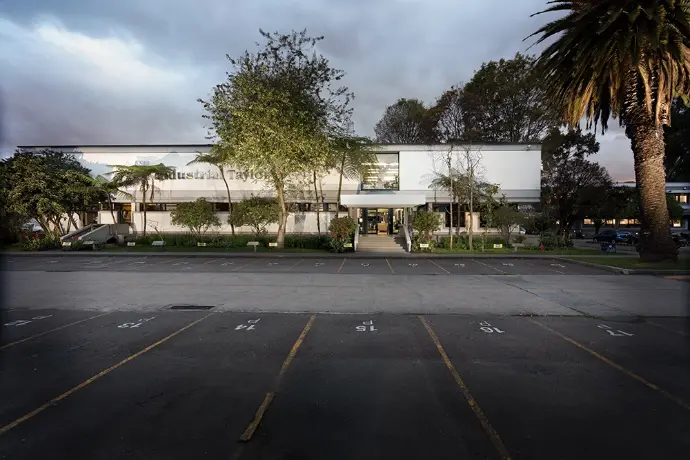 Exterior del edificio de oficinas Industrial Taylor, con un estacionamiento y palmeras.